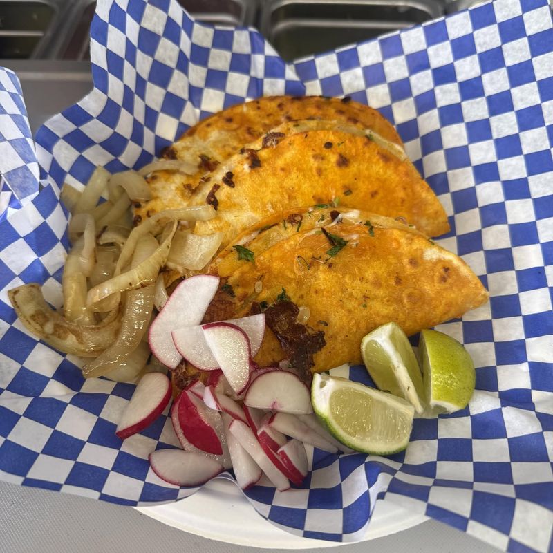 Crispy quesabirria tacos on checkered paper with grilled onions, radish and lime